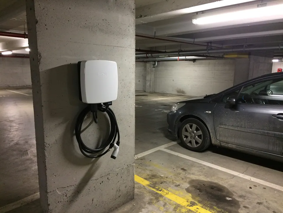 Borne de recharge murale fixée sur un pilier de parking souterrain d'immeuble